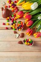 Tulpen und Schokoladenostereier auf einem hölzernen Hintergrund