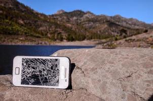 kaputtes Telefon auf einem Felsen foto
