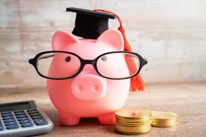 Schweinchen Bank tragen Brille mit mit Münzen und Taschenrechner Speichern Bank Bildung Konzept. foto