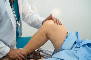 asiatischer Arzt Physiotherapeut untersucht, massiert und behandelt Knie und Bein eines älteren Patienten im Krankenschwesterkrankenhaus der orthopädischen Klinik. foto