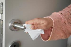 Frauen Hand Reinigung Tür Knopf mit Gewebe schließen oben foto