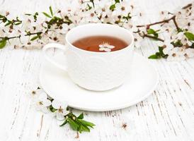 Tasse Tee und Frühlings-Aprikosenblüten auf einem hölzernen Hintergrund foto