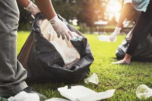 Mutter und Kinder behalten Müll Plastik Flasche in schwarz Tasche beim Park im Morgen Licht foto