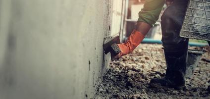 Nahansicht Hand Arbeiter Verputzen Zement auf Mauer zum Gebäude Haus foto