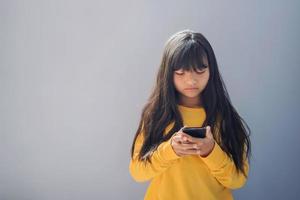 Kind mit Handy, Mobiltelefon auf Blau Hintergrund foto