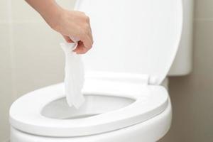 Nahaufnahme der Hand, die ein Gewebe hält, das in die Toilettenschüssel geworfen werden soll. kann das Wasser des Toilettenpapiers nicht in die Toilettenschüssel abfließen, was dazu führen kann, dass der Stuhl verstopft. foto