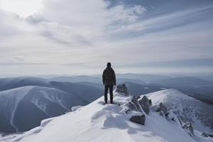 Mann Stehen auf das oben von ein schneebedeckt Berg Gipfel. Panorama- Aussicht foto