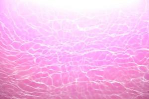 defokussieren verschwommen transparent Rosa farbig klar Ruhe Wasser Oberfläche Textur mit Spritzen, Blase. leuchtenden lila Wasser Welligkeit Hintergrund. Oberfläche von Wasser im Schwimmen Schwimmbad. lila Blase Wasser scheinen. foto