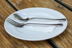 Gabel und Löffel mit weißer Platte auf Holztisch foto