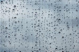 Wasser Tropfen auf Glas Fenster mit Moskito Netz gegen grau Himmel foto