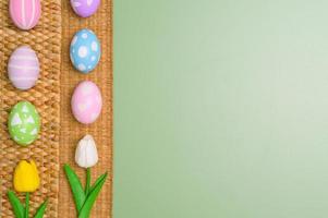 glücklich Ostern Urlaub Gruß Karte Design Konzept. bunt Ostern Eier und Frühling Blumen auf Pastell- Grün Hintergrund. eben legen, oben Sicht, Kopieren Raum. foto