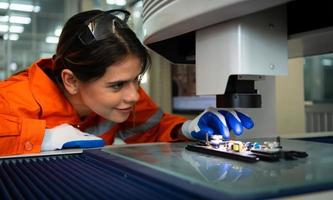 weiblich Ingenieurwesen und ein klein Schaltkreis Tafel zu Sein Eingerichtet im ein Roboter Hand. zu Dienen wie ein Vermittler zum Empfang und Senden ein einstellen von Anleitung zum das Roboter Hand Arbeit automatisch. foto