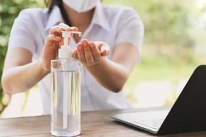 Frau mit Alkohol Gel von Flasche und bewirbt sich Desinfektionsmittel zum Hand machen Reinigung Virus covid 19 foto