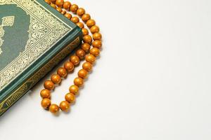 das heilig al Koran mit geschrieben Arabisch Kalligraphie Bedeutung von al Koran und Rosenkranz Perlen oder tasbih auf Weiß Hintergrund, isoliert mit Kopieren Raum. foto