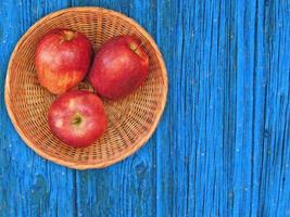 rote Äpfel auf einem Weidenteller auf einem hölzernen Tischhintergrund foto