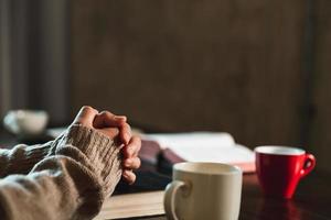 christliches lebenskrisengebet zu gott. Frau betet um Gottes Segen, um sich ein besseres Leben zu wünschen. frauenhände beten mit der bibel zu gott. um Vergebung bitten und an das Gute glauben. foto