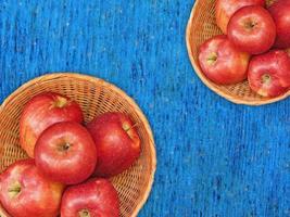 rote Äpfel auf einem Weidenteller auf einem hölzernen Tischhintergrund foto