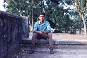 Rangpur, Bangladesch 2023. deprimiert Teenager Mann Sitzung allein auf Mauer im im Freien.unangenehm Schmerz. traurig unzufrieden gut aussehend man.bangladesch und Asien Junge Leiden Depression. foto