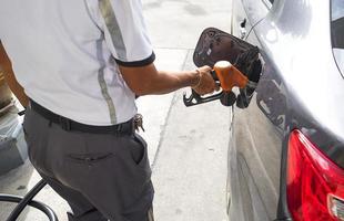 Mann, der Benzinkraftstoff im Auto an einer Tankstelle pumpt foto