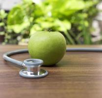 grüner Apfel mit einem Stethoskop, Gesundheitskonzept foto