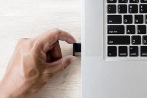 Hand Einsetzen einer Speicherkarte in einen Laptop-Steckplatz foto