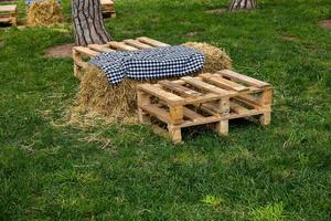 Picknick Stelle auf Grün Gras auf ein Sommer- Tag mit Stroh Tabellen und hölzern Kisten foto