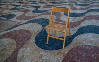 Erklärung Promenade im alicante Spanien Wahrzeichen mit hölzern leeren Stuhl auf Mosaik foto