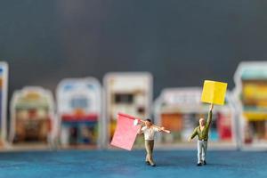 Miniaturmenschen, Demonstranten, die Schilder halten, ihre Hände für die Revolution heben, gegen das Konzept protestieren foto