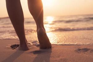 Füße gehen langsam, Leben und Entspannung auf einem tropischen Sandstrand mit einem blauen Himmelhintergrund foto