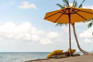Regenschirm und Stuhl an einem tropischen Sommerstrandhintergrund mit blauem Himmel des Kopierraums foto