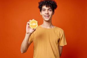 Kerl T-Shirt mit Orange im seine Hände Obst gesund Essen foto