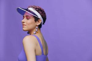 Porträt von ein sportlich Mode Frau posieren lächelnd im ein lila Sport passen zum Yoga und ein transparent Deckel auf ein lila Hintergrund einfarbig foto