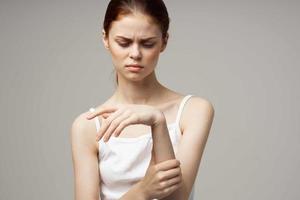 Frau im Weiß T-Shirt Arm Schmerzen Arthritis chronisch Krankheit Licht Hintergrund foto