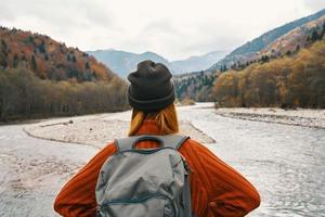 Frau im ein Sweatshirt und Deckel mit ein Rucksack auf ihr zurück im das Berge auf Natur Landschaft foto