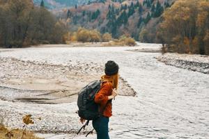 Frau ruhen auf das Fluss Bank im das Berge auf Natur Landschaft und Modell- Rucksack Tourismus foto