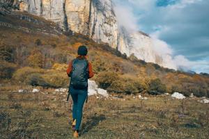 Frau im Jeans Stiefel und ein Sweatshirt mit ein Rucksack sind ruhen im das Herbst im das Berge im Natur foto