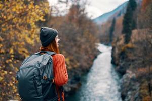 Frau Wanderer mit Rucksack auf ihr zurück in der Nähe von Berg Fluss im Natur foto