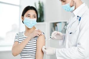 ein Arzt spritzt ein Impfstoff zu ein weiblich geduldig covid foto