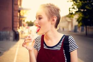 ziemlich Frau draußen Essen Eis Sahne gehen foto