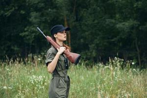 Frau mit ein Gewehr auf seine Schulter, ein schwarz Deckel ist ein Weg von Leben zum Jagd Grün Overall foto