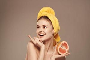 Frau mit ein Handtuch auf ihr Kopf Grapefruit im ihr Hände Gesundheit Vitamine entblößt Schultern foto