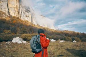 Reisender mit Rucksack im Herbst im das Berge Blau Himmel Wolken hoch Felsen Landschaft foto