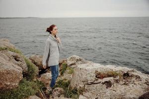Frau im ein grau Sweatshirt steht auf ein felsig Ufer Natur unverändert foto