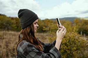 Porträt von ein Frau im ein medizinisch Maske mit ein Telefon auf das Hintergrund von ein Herbst Wald im Natur foto