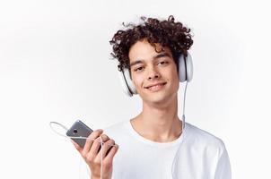Kerl mit lockig Haar im ein Weiß T-Shirt hört zu zu Musik- Technologie foto
