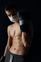 Boxer tragen medizinisch Maske nackt Torso schwarz Hintergrund abgeschnitten Aussicht foto