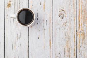 Kaffeetasse mit Kaffee auf einem Holzschreibtisch gefüllt foto
