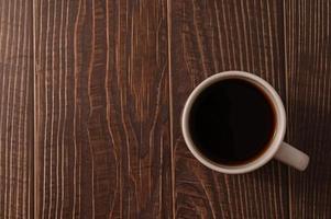 Kaffeetasse mit Kaffee auf einem Holzschreibtisch gefüllt foto