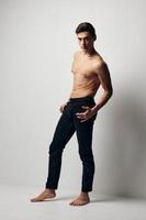 ein Mann im Jeans mit ein nackt Torso im voll Wachstum Modell- im ein hell Zimmer foto
