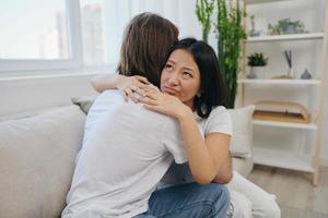 ein Mann Umarmungen seine asiatisch Frau Freund beim heim. psychologisch Unterstützung zum ein Freund foto